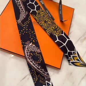 Twilly Hermès "The Three Graces" en soie, de couleur noir et bleu.